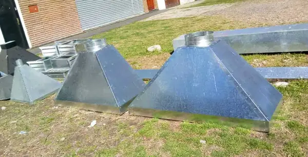 Campanas de extracción terminadas, apoyadas afuera del taller.